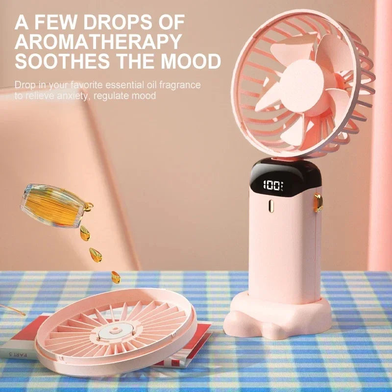 Pink handheld fan with essential oil dropper on a checkered tablecloth